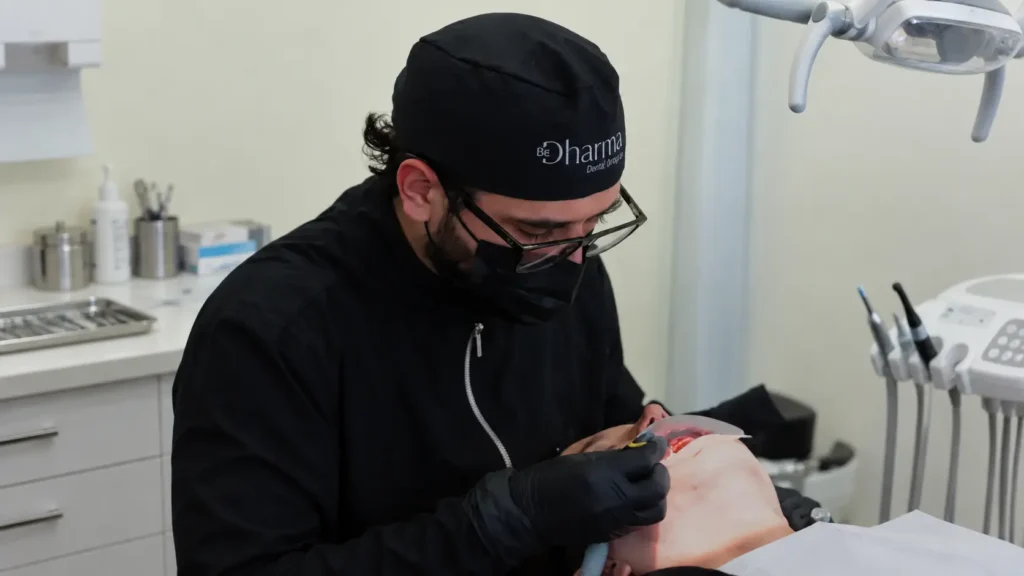 Odontólogo de Be Dharma Dental realizando un procedimiento dental en consultorio con guantes negros